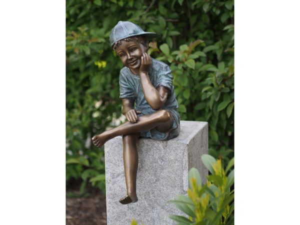 Bronzefigur Sitzender Junge mit Mütze