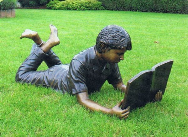 Bronzefigur Junge liegend lesend